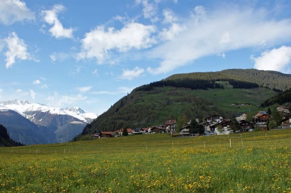 Curaglia, village du Val Medel dans les Grisons : les maisons, les prés de printemps et les montagnes
