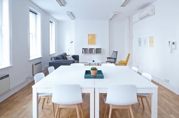 Photographie d’illustration : un espace de travail lumineux, avec une grande table, des chaises et un coin salon. Ce n’est pas un local que nous proposons.